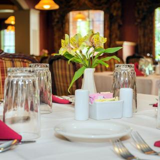 A beautifully arranged dining table in a restaurant, complete with glasses, a vase of flowers, and neatly placed napkins.