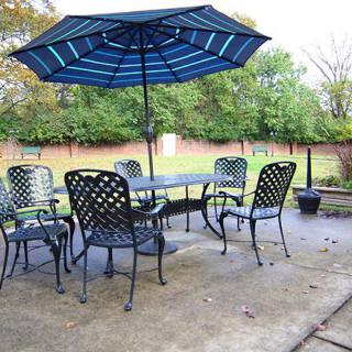 Outdoor patio set with a blue umbrella and metal chairs in a backyard setting.