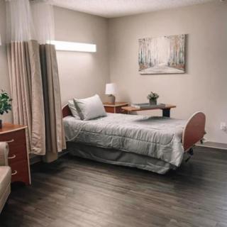 A modern bedroom with a single bed, nightstand, lamp, and minimalist decor.