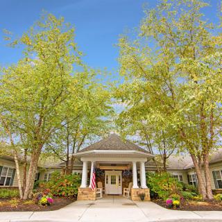 A welcoming entrance to a building surrounded by trees and landscaping on a clear day.