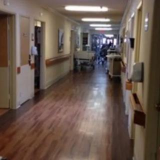 A view down a hospital hallway with medical equipment and rooms on either side.
