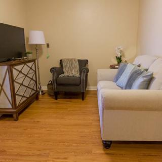 A cozy living room with a sofa, TV stand, armchair, and lamp.