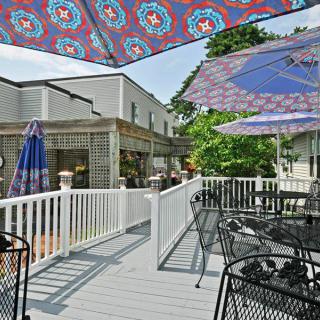 A sunny outdoor deck featuring colorful umbrellas, tables, and chairs.