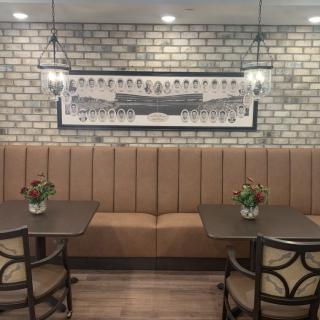 A cozy restaurant interior featuring booth seating, a brick wall backdrop, and ambient hanging lights.