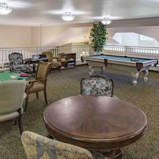 A cozy indoor game room with a pool table and poker table, surrounded by comfortable seating.