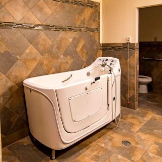 A bathroom featuring a walk-in tub with tiled walls and floor.