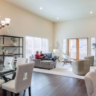A spacious and modern living room with an open dining area, featuring cozy furniture and ample natural light.