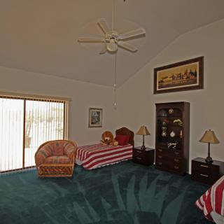 A spacious bedroom with twin beds, carpeted floor, and cozy furniture.