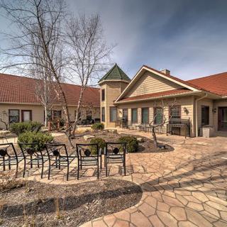 A serene courtyard featuring outdoor seating and landscaping, surrounded by a rustic building.