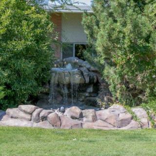 A small waterfall feature in a garden surrounded by lush greenery and rocks.