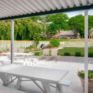 A serene outdoor patio area with a dining table, overlooking a well-maintained garden and yard.