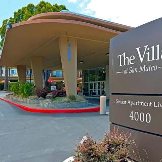 The entrance to The Village at San Mateo with a prominent sign and landscaping.