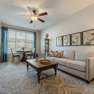 A cozy living room with a comfortable sofa, coffee table, and dining area by the window.