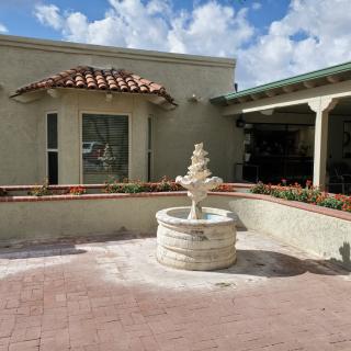 A courtyard with a decorative fountain surrounded by a building under a partly cloudy sky.
