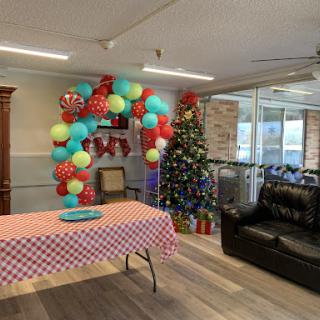 A festive celebration setup featuring colorful balloons and a Christmas tree, ready for an event.