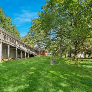 A spacious backyard with a large lawn, surrounded by trees and featuring an elevated deck.