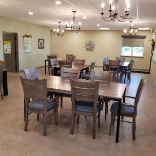 A spacious and elegantly decorated dining room with multiple tables and chandeliers.
