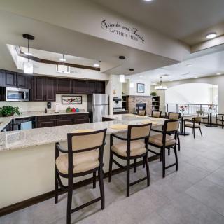 A modern kitchen with an open dining area featuring bar stools at the island and stylish pendant lighting.