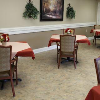 A cozy dining area featuring tables with red tablecloths and elegant chairs, complemented by decorative plants on the walls.
