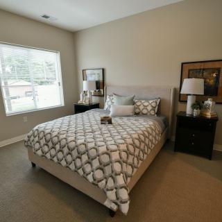 A cozy bedroom with a neatly made bed, nightstands, and decorative elements.