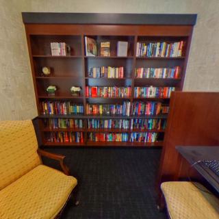 A cozy library corner featuring a wooden bookshelf filled with books and comfortable seating.