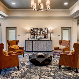 Elegant living room with plush armchairs and a modern chandelier.
