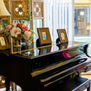 A grand piano adorned with flowers and photo frames in a cozy living room.