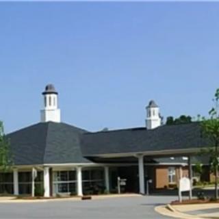A building with cupolas and a covered entrance set in a landscaped area.