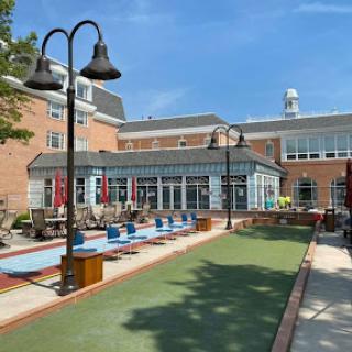 A beautiful outdoor recreational area featuring seating, a lawn, and modern architecture under a clear blue sky.