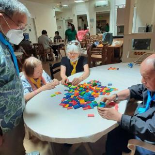 A group of seniors engaging in a creative building blocks activity at a community center.