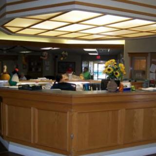 A wooden reception desk in a lobby with decorative flowers on top.