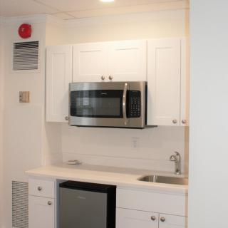 A compact modern kitchen with white cabinets and built-in appliances.