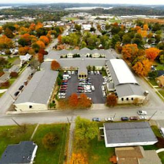 Aerial view of a small town with buildings, colorful autumn trees, and a parking lot.
