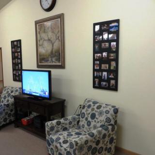 A cozy living room with patterned chairs, a television, and wall decor.
