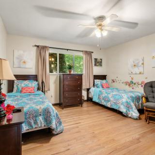A cozy bedroom with twin beds, colorful bedding, and a ceiling fan.