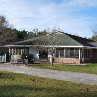 A single-story residential house surrounded by trees and a lawn.