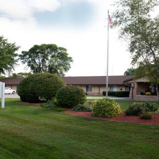 A well-maintained building surrounded by lush greenery and a flagpole.