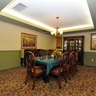 A well-furnished dining room featuring a large dining table with chairs, a chandelier, decorative artwork, and carpeted flooring.