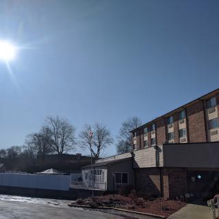 A sunny day with clear blue skies over a building next to a parking lot.