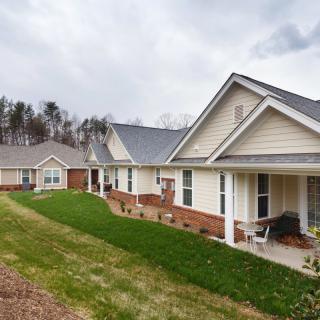 A row of suburban houses with manicured lawns and porches.