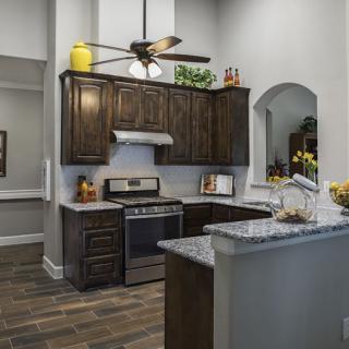 A modern kitchen with dark wood cabinets, granite countertops, and stainless steel appliances.