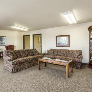 A living room with patterned sofas, a wooden coffee table, carpeted flooring, and wall decorations.