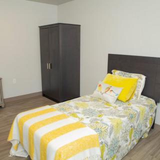 A simple bedroom with a single bed and a wardrobe.