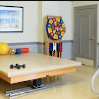 A physical therapy room equipped with various exercise tools and a treatment table.