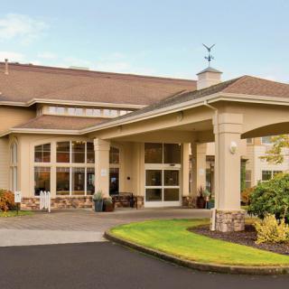 A modern building entrance with large windows and well-maintained landscaping.
