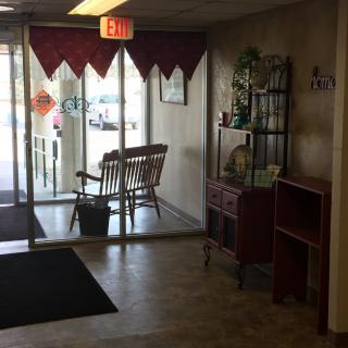 A cozy waiting area with a wooden bench near glass entrance doors.