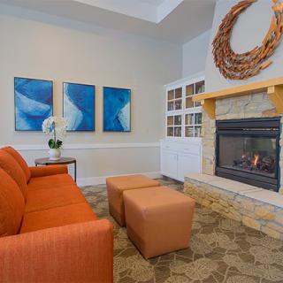 A modern living room with an orange couch, a fireplace, and blue artwork on the wall.