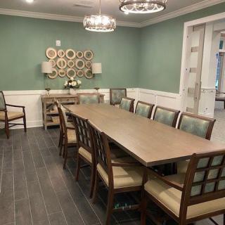 A well-furnished dining room with a large table, surrounded by chairs, and adorned with elegant chandeliers.