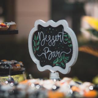 A decorative chalkboard sign displaying 'Dessert Bar' at an event.