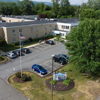 Aerial view of a facility featuring parking spaces and surrounding greenery.